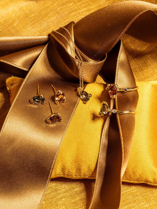 Stilleben med eleganta smycken i guld på guldkudde och satinband, lyxig känsla