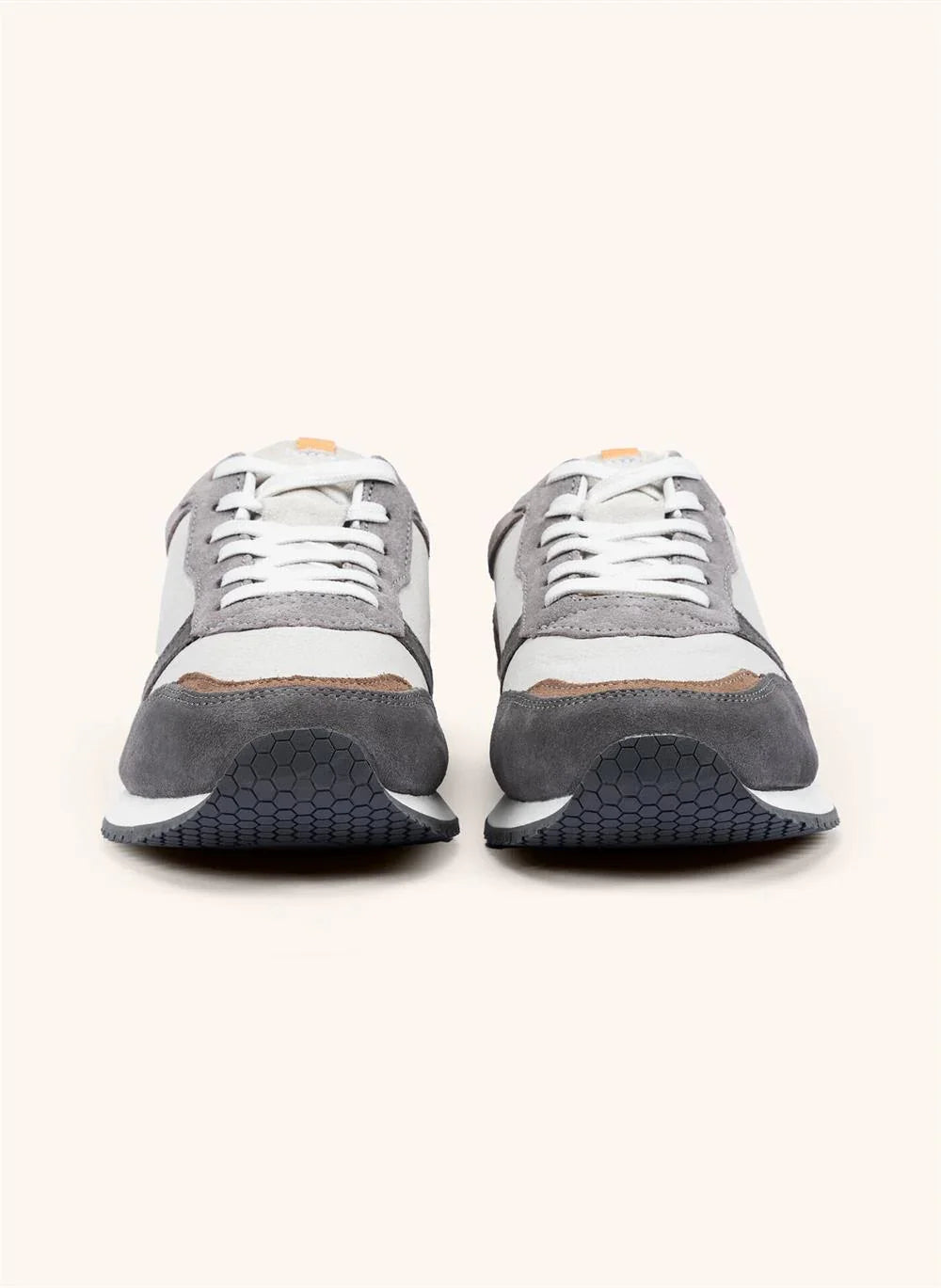 Gråvita herrsneakers i mocka och textil med vita skosnören, set framifrån på ljus bakgrund