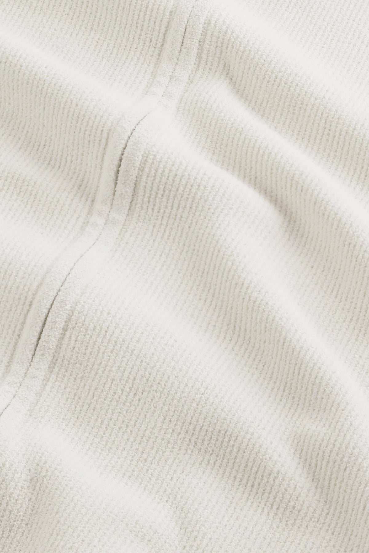 Närbild på vit ribbad textil i ett plagg för herr