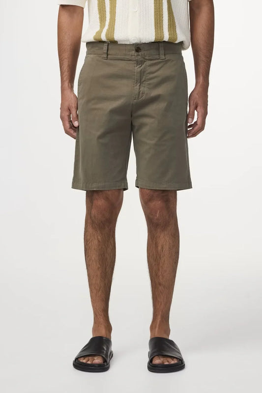 Herr i olivgröna shorts och sandaler, sommarkläder för män mot vit bakgrund.