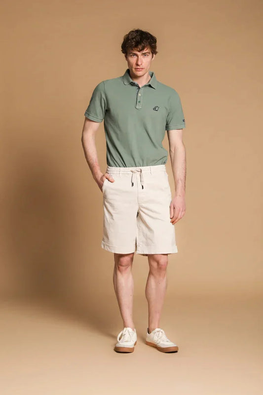 Man i ljusgrön pikétröja och beige shorts, klassisk herrklädsel, sommarstil.