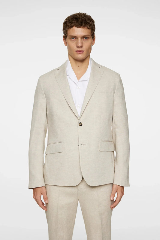 Man i ljusbeige linnekostym med vit skjorta, klassiskt herrmode, neutral bakgrund