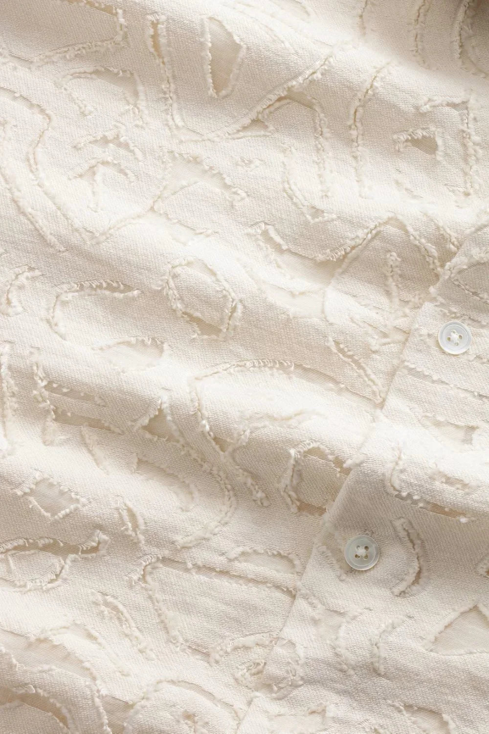 Närbild av beige herrskjorta med strukturmönster och knapp, klassiskt herrmode tyg