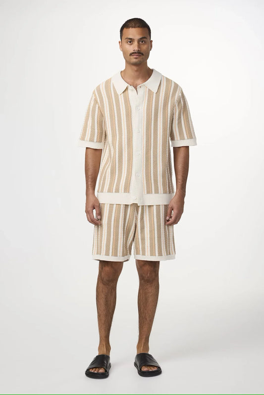 Man i beige och vit randig skjorta och shorts, klassiska herrkläder, sommarkläder.