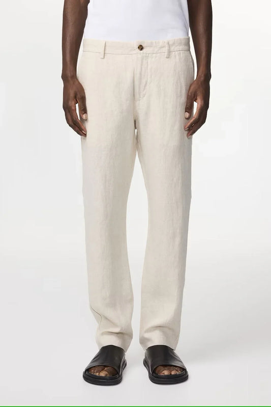 Herrmodell med beige linnabyxor, vit t-shirt och svarta sandaler, klassisk stil