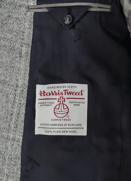Närbild av Harris Tweed-etikett på grå herrkavaj, 100% ull, klassiskt herrmode.