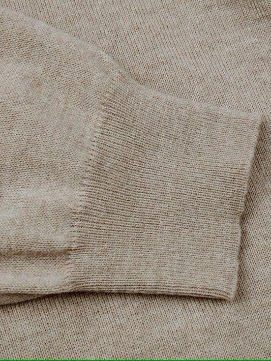 Beige stickad herrtröja med nära bild på ärmslut i ullmix