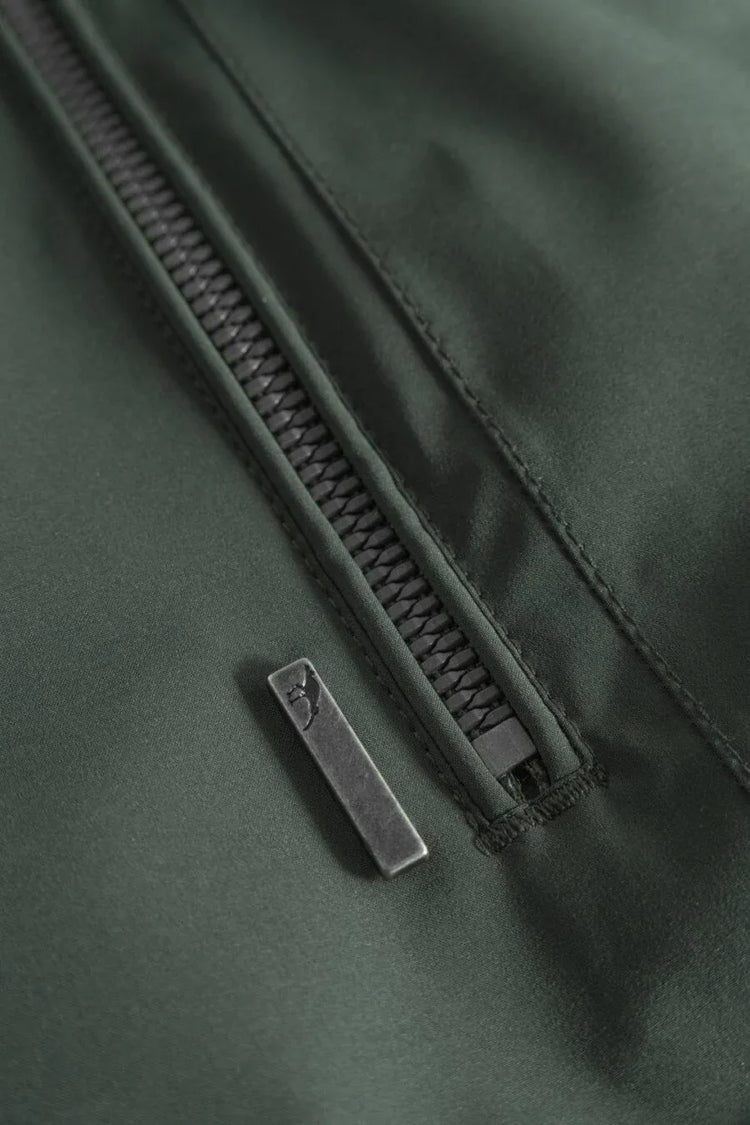 Närbild av grön jacka i herrmodell med svart dragkedja och detaljerad sömnad.