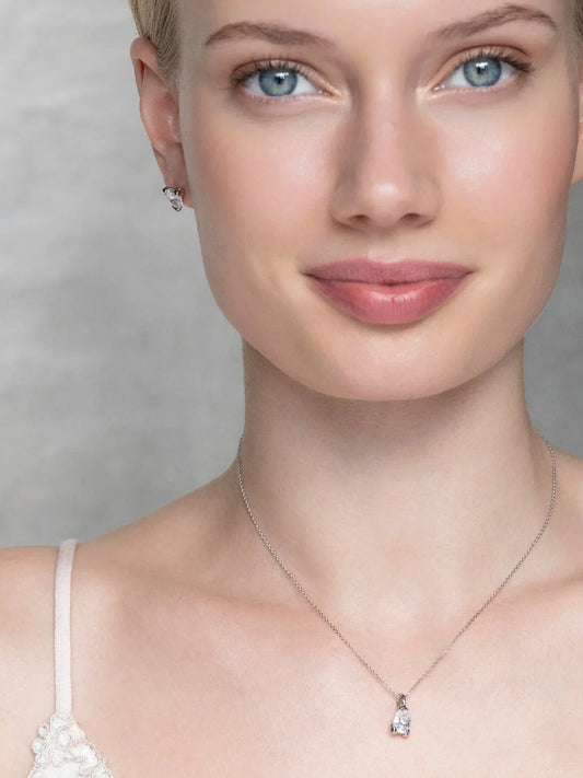 Kvinna med ljusa ögon bär ett elegant halsband och örhängen i silver med stenar
