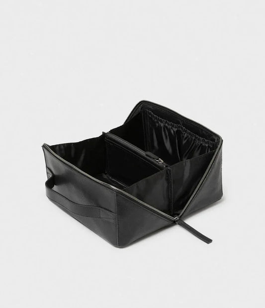 Svart necessär i läder med dragkedja och flera fack, herraccessoar mot vit bakgrund.