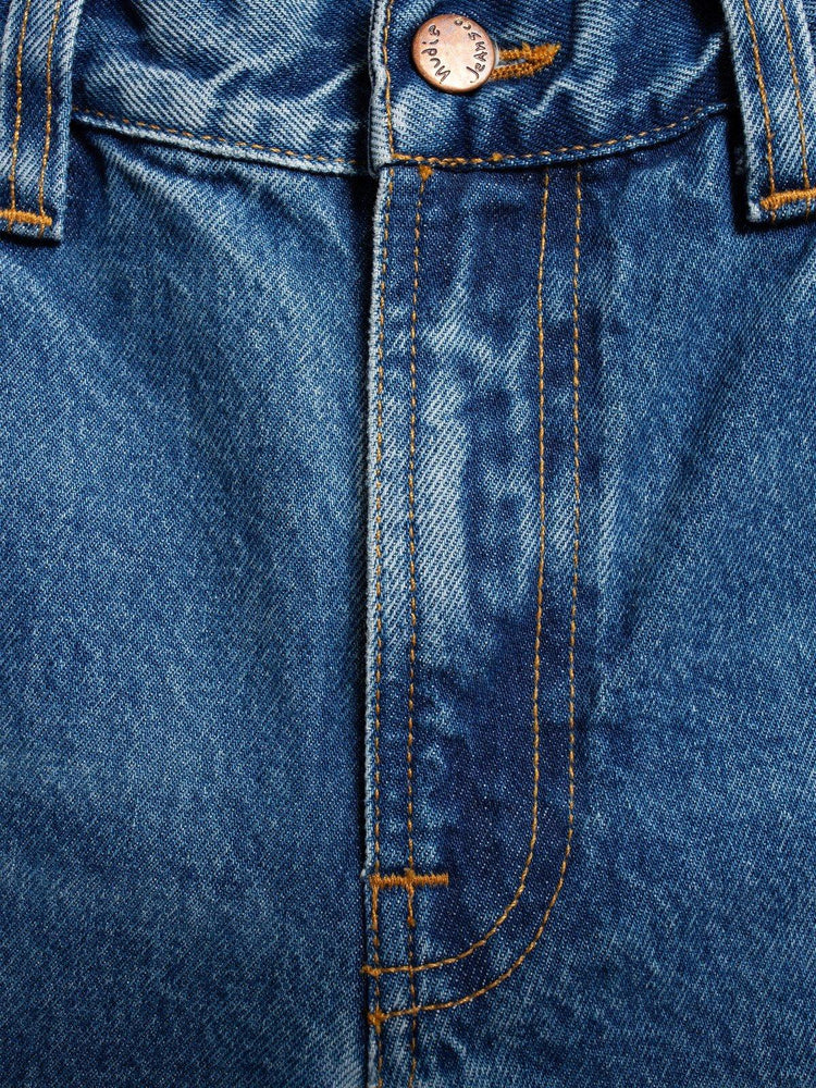 Närbild på blå herrjeans med synliga sömmar och knapp, klassiska denimbyxor