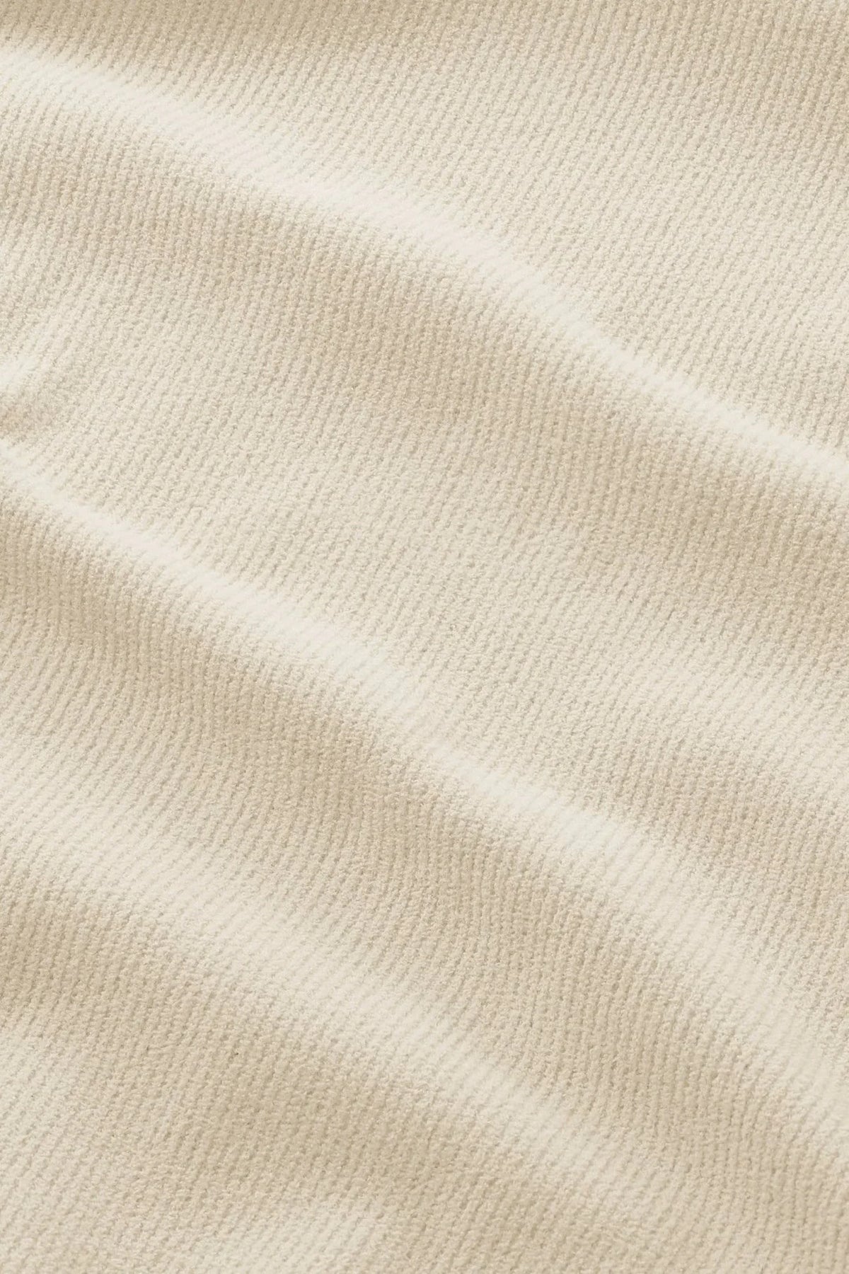 Närbild på beige strukturerat tyg för herrkläder med subtil ribbad yta