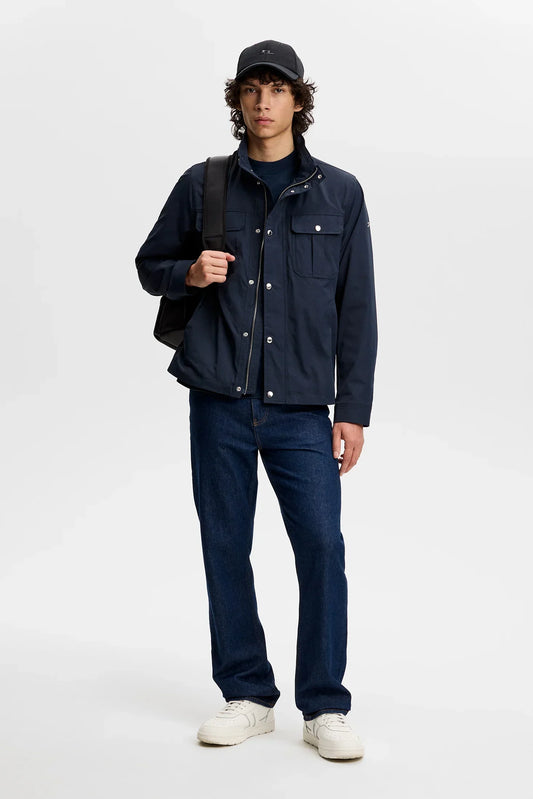 Mörkblå herrjacka, raka jeans, vita sneakers, svart keps