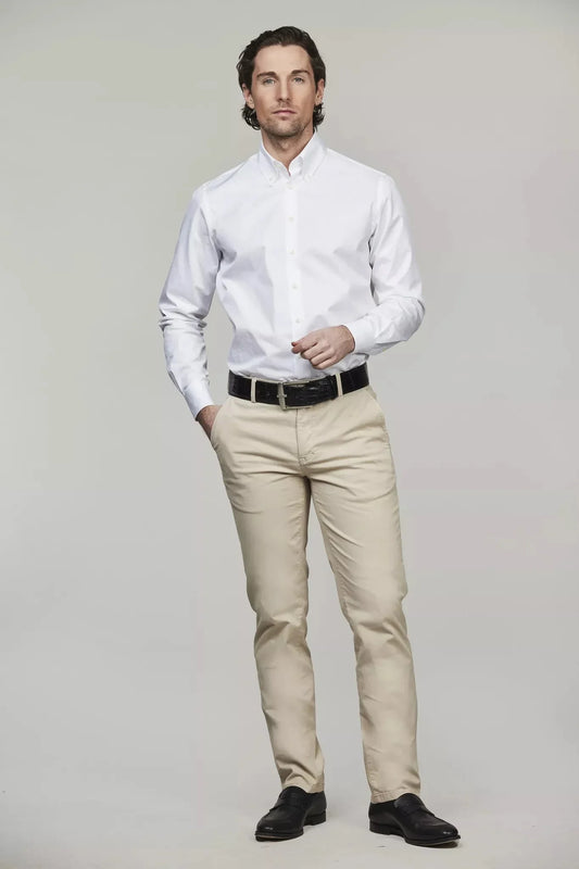Man i vit skjorta och beige stretch-chinos, klassisk herrstil, studiofoto.
