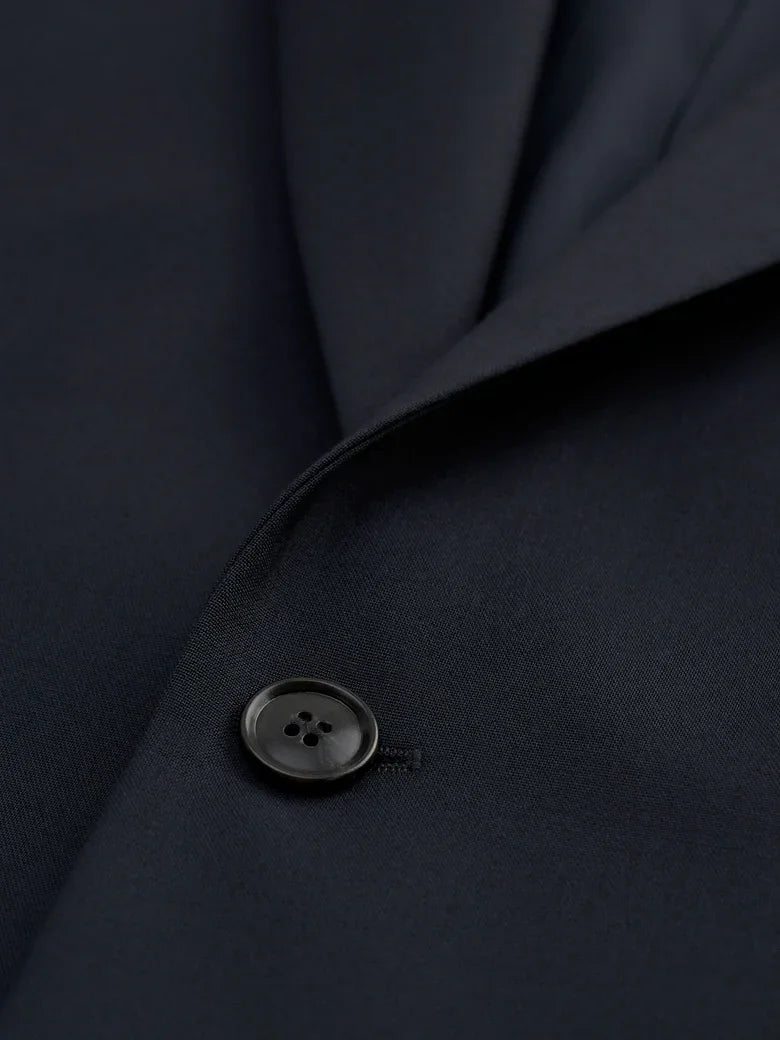 Detaljbild av mörkblå kavaj i herrmodell, fokus på knapp och tyg