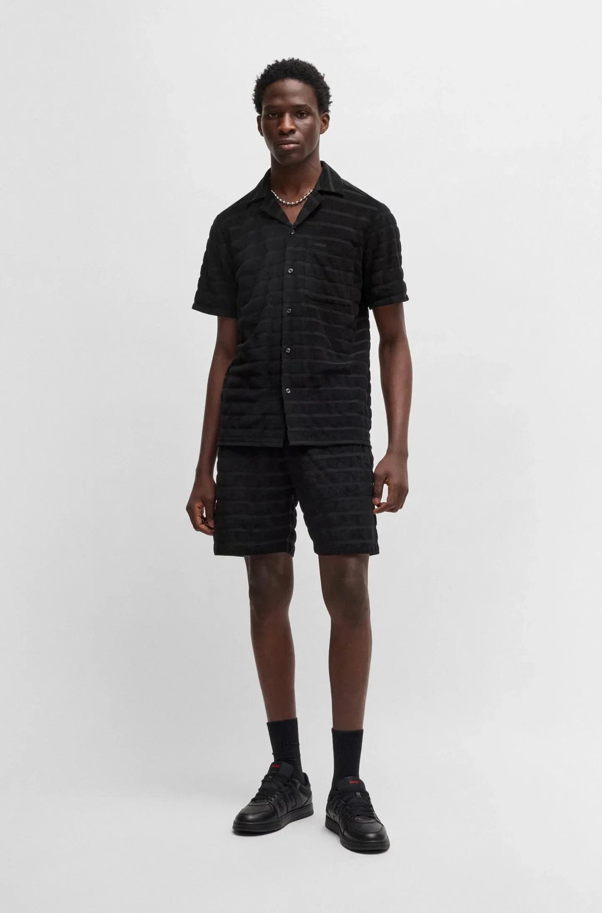 Man i svart kortärmad skjorta och shorts, herrmode, enkel bakgrund