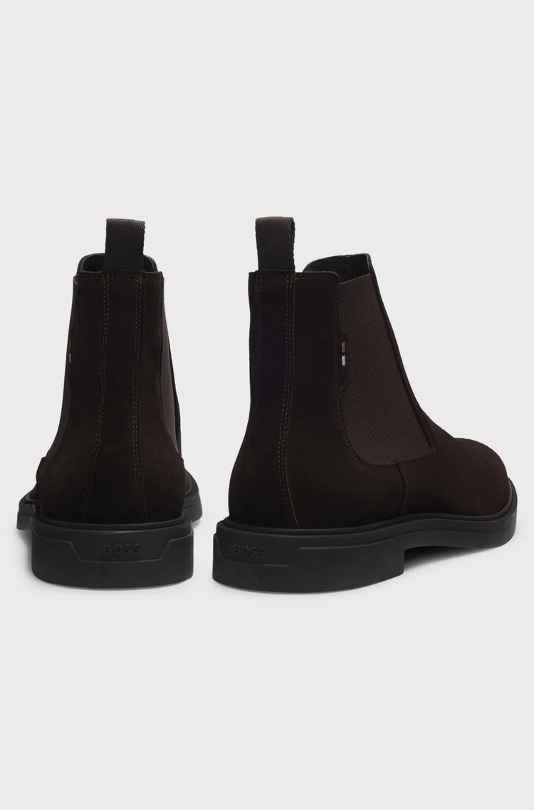 Mörkbruna herr Chelsea boots i mocka med grov sula, visade bakifrån mot vit bakgrund