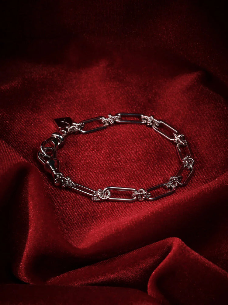 Snyggt herrarmband i silver med detaljer, presenterat på röd sammetstyg.