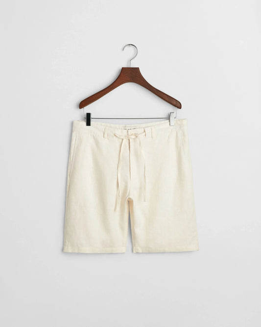 Beige herrshorts i lin med knytband, hänger på trägalge mot vit bakgrund.