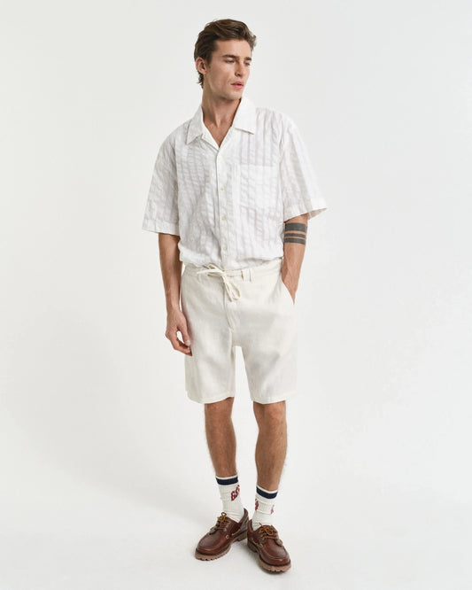Man i ljus skjorta med kort ärm och short, klassiskt herrmode i sommarstil.