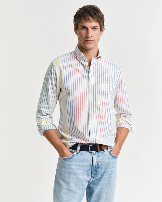 Man i randig skjorta och ljusa jeans, klassiskt herrmode mot vit bakgrund.