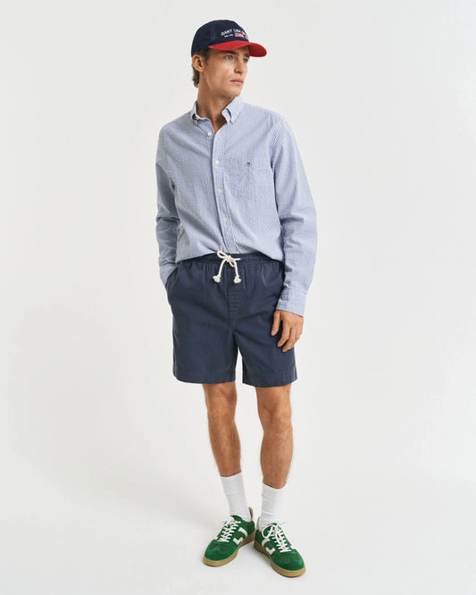 Man i blå randig skjorta, mörkblå shorts och keps, herrmode, casual stil