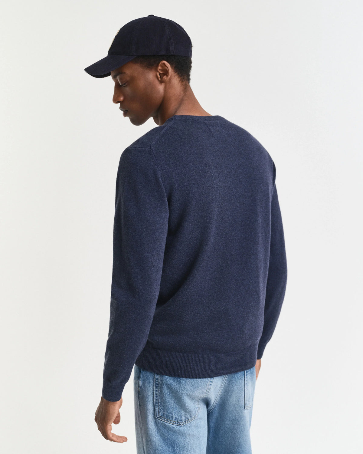 Marinblå herr tröja – Holmens Herr, stickad tröja, modell bakifrån, jeans, keps