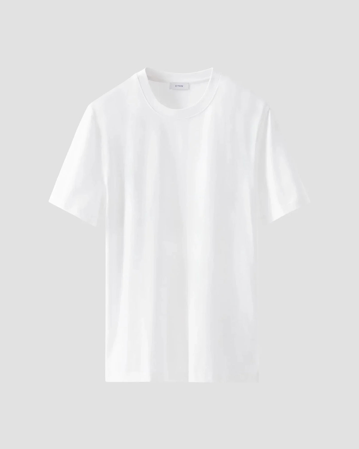 Klassisk vit t-shirt i bomull för herr, kort ärm, rund hals, mot ljus bakgrund.