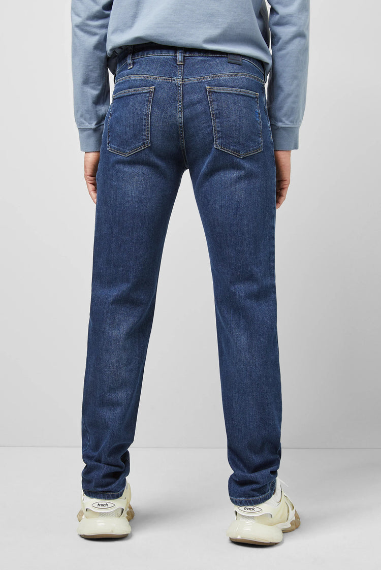 Herr i blå raka jeans, vit sneakers, bakifrån mot ljus vägg, herrkläder mode