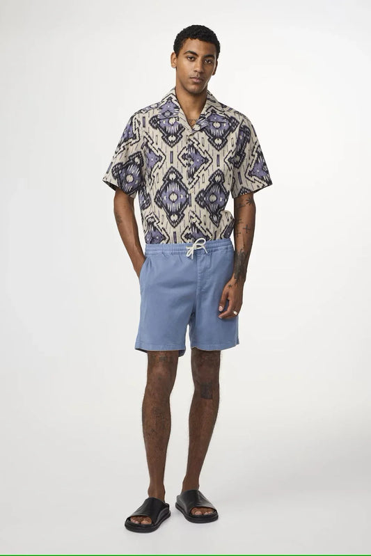 Man i mönstrad kortärmad skjorta och ljusblå shorts, sommarkläder herrmode
