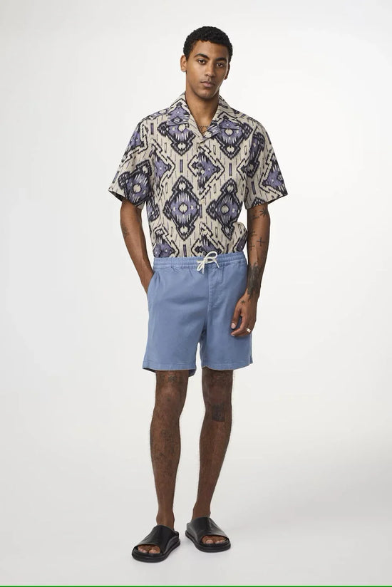Man i mönstrad kortärmad skjorta och ljusblå shorts, sommarkläder herrmode