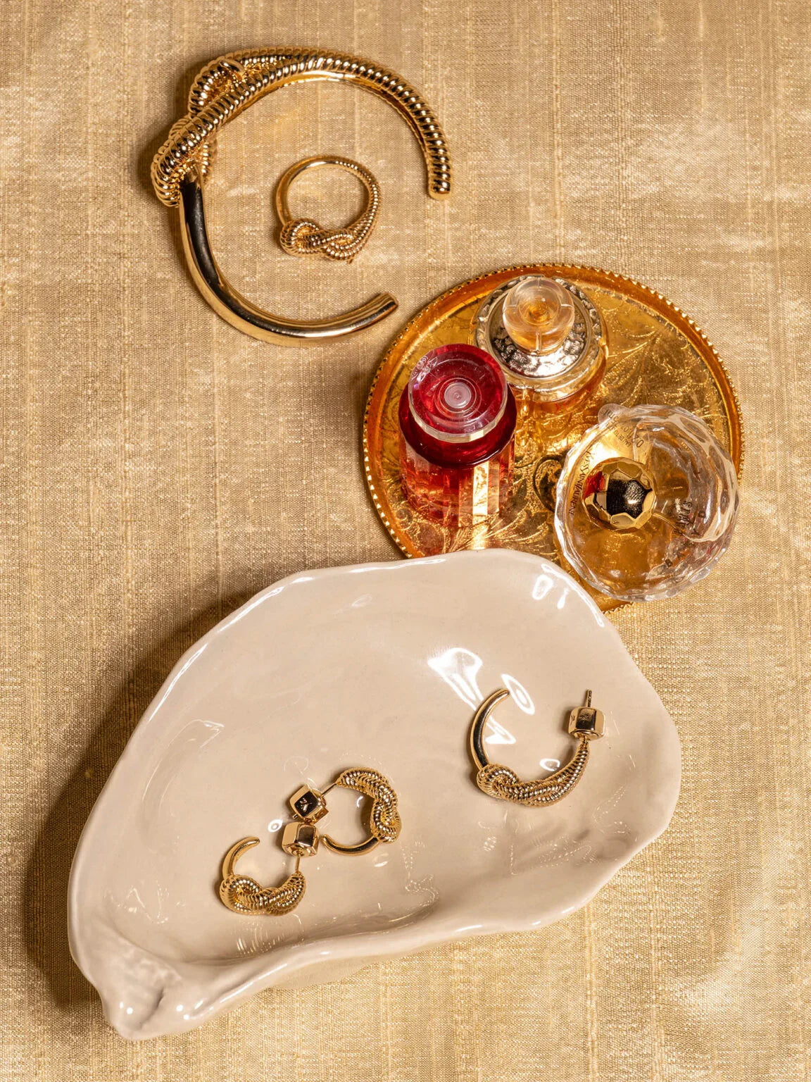 Stilleben med guldsmycken och parfymflaskor på beige duk, elegant herraccessoar