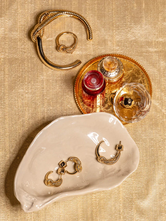 Stilleben med guldsmycken och parfymflaskor på beige duk, elegant herraccessoar