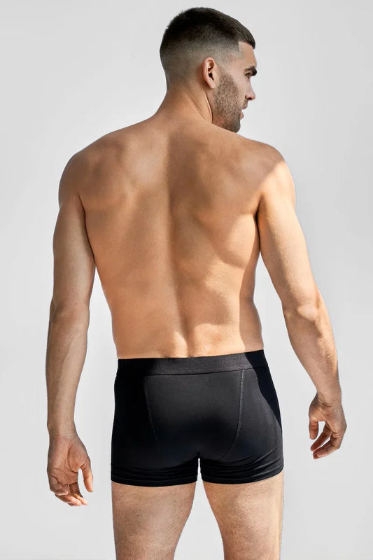 Manlig modell bakifrån bär svarta boxer briefs, herrunderkläder, neutral bakgrund
