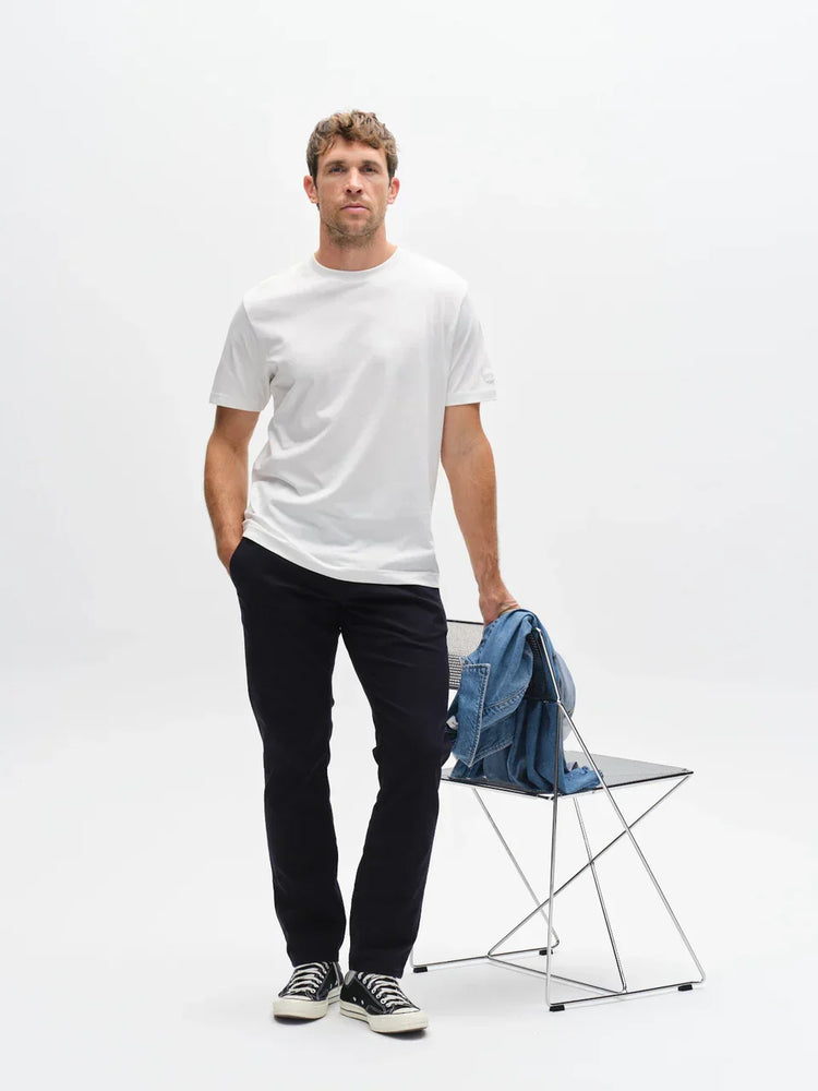 Vit t-shirt herr, svarta byxor, svartvita sneakers, jeansjacka på stol