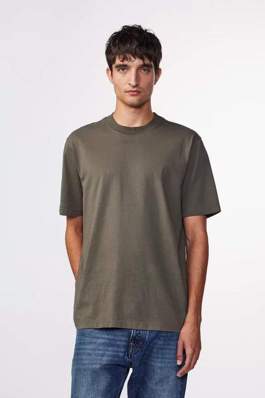 Man i olivgrön t-shirt och blå jeans, klassiskt herrmode, vit bakgrund