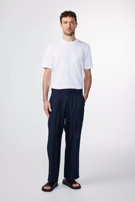 Man i vit t-shirt, mörkblå byxor och svarta sandaler på vit bakgrund