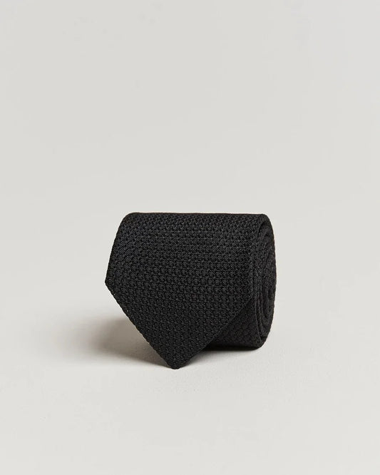 Svart stickad slips i elegant herrstil på ljus bakgrund