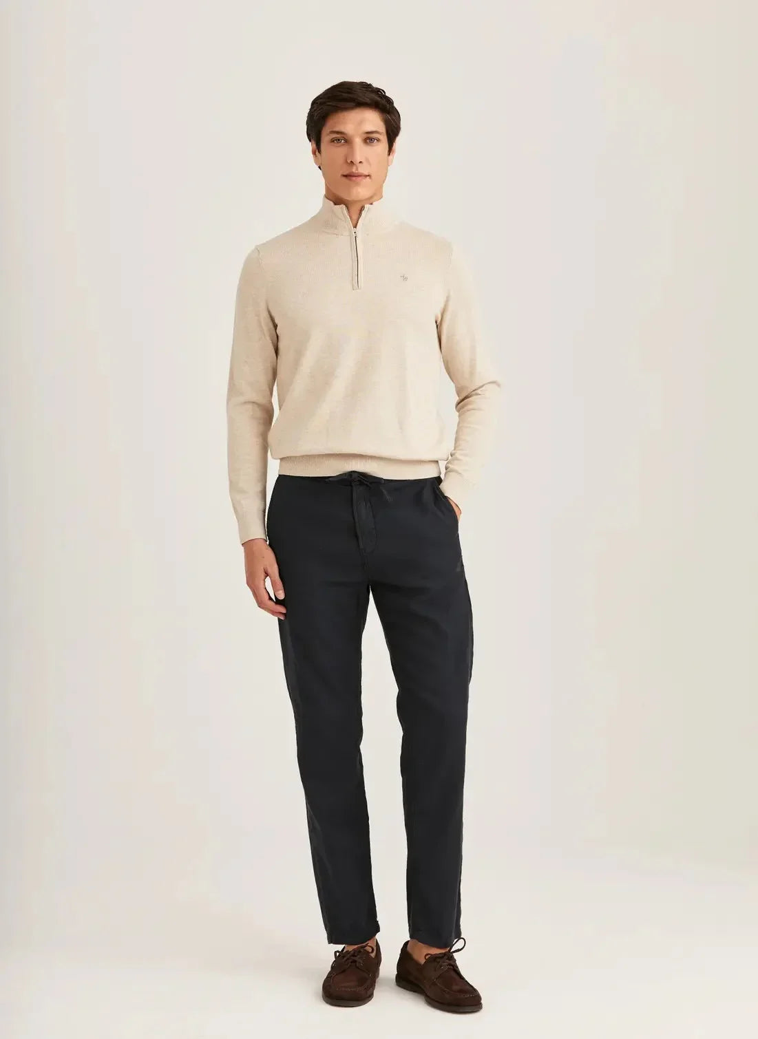 Man i beige stickad tröja och mörkblå linnabyxor, herrmode, neutral bakgrund