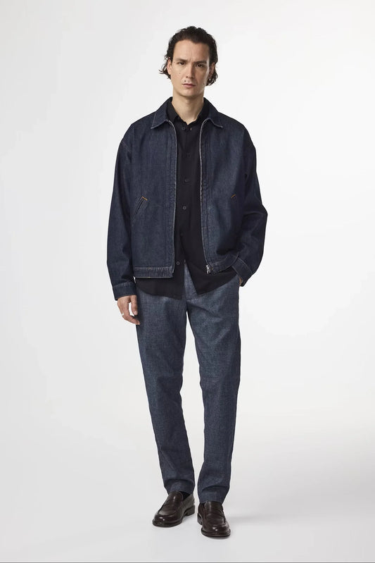 Modell bär herr jacka och byxor i denim, svart skjorta och mörka loafers