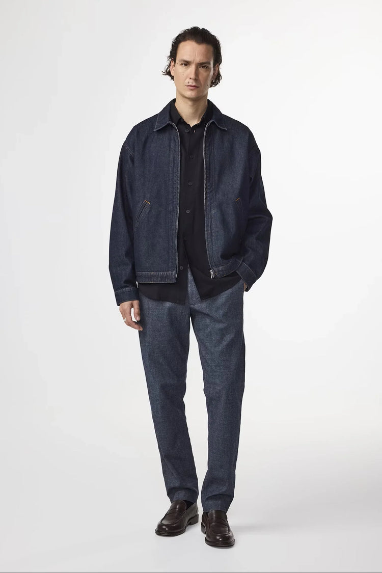 Modell bär herr jacka och byxor i denim, svart skjorta och mörka loafers