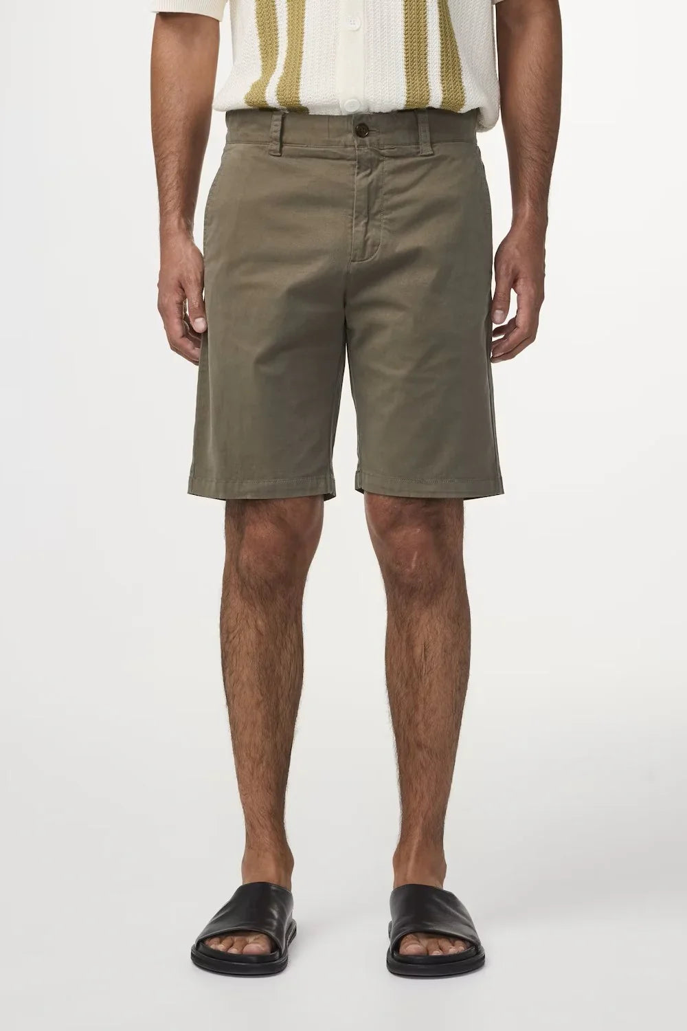 Herr i olivgröna shorts och sandaler, sommarkläder för män mot vit bakgrund.