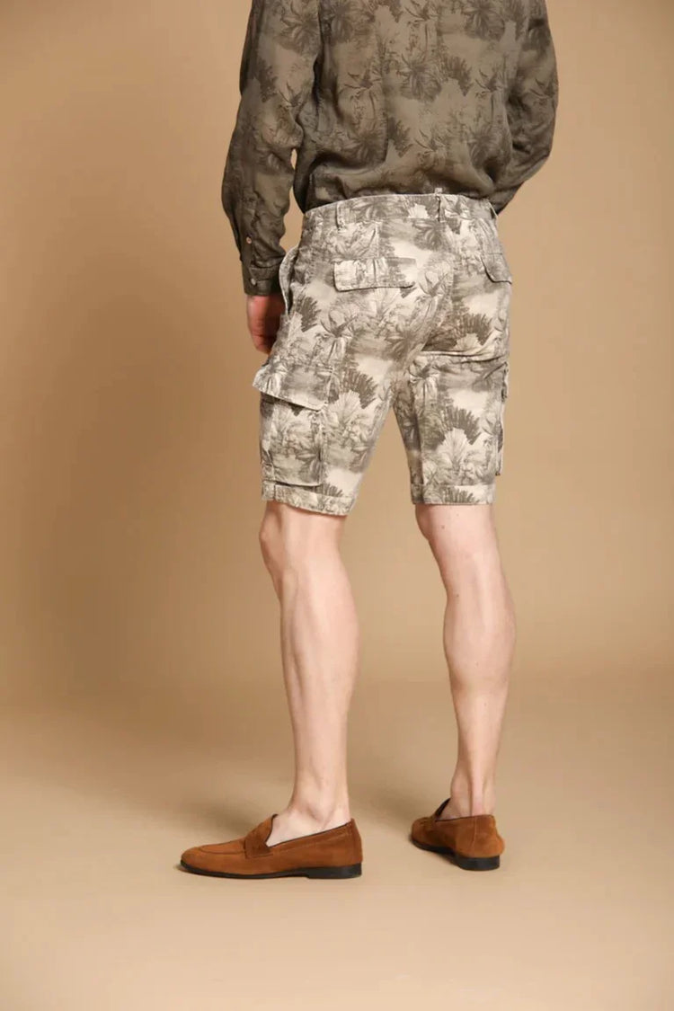 Herr i beige mönstrade cargoshorts och brun skjorta, bruna loafers, neutral bakgrund