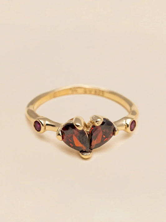 Guldring med röda hjärtformade stenar och små lila ädelstenar, elegant design.