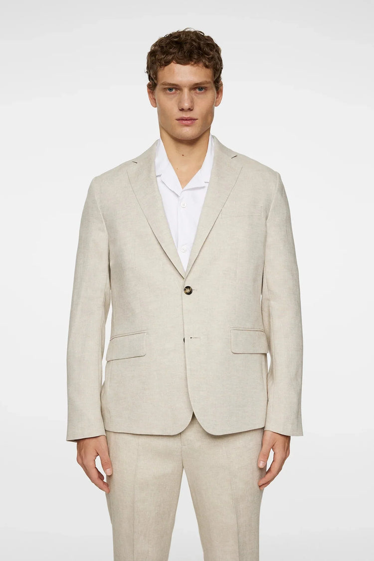 Man i ljusbeige linnekostym med vit skjorta, klassiskt herrmode, neutral bakgrund