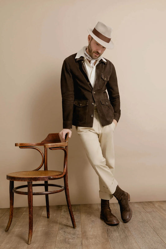 Brun skinnjacka herr med beige byxor och vit hatt