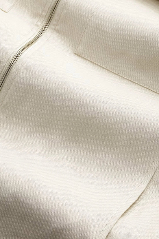 Närbild på beige bomullstyg med dragkedja och ficka, herrkläder detalj.