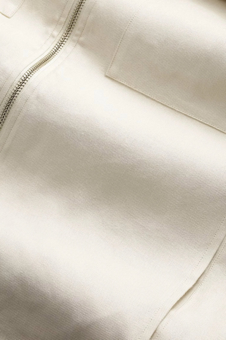 Närbild på beige bomullstyg med dragkedja och ficka, herrkläder detalj.