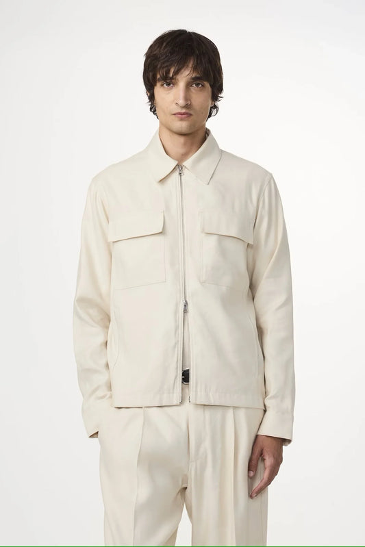 Man i beige skjorta och byxor, klassisk herrstil mot vit bakgrund