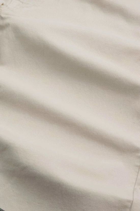 Närbild av beige bomullstyg med synlig söm, herrkläder materialstruktur